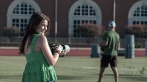 Camera in hand, junior Isabelle Oathout photographs a varsity football practice. Oathout is a part of the Football Operations program run by Malcolm Hill. The Football Operations team works to run and organize practices and games.